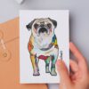 Die Postkarte ist ein Kunstdruck mit einem bunt gestalteten Mops, namens Sofie, die mit großen dunklen Kulleraugen ihren Betrachter erwartungsvoll anblickt. Wohl wissend, dass sie gleich ihren Hundefreund, die Dogge Bob, trifft.