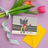 Die lustige Postkarte zeigt den bunt gemusterten Dickhäuter von hinten, der fröhlich mit erhobenen Rüssel seinen Weg geht und ein „Be Happy“ vor sich her trötet. Mit Liebe designed von der Regensburger Künstlerin Sabine Leipold.