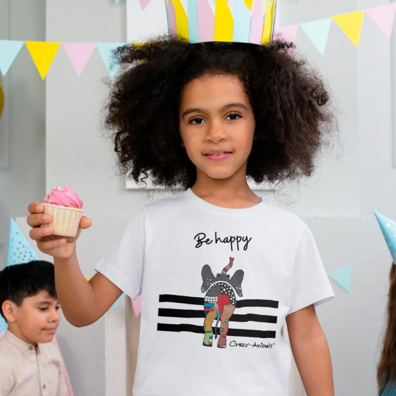 Weißes Kinder T Shirt mit einem bunt gemusterten Dickhäuter von hinten, der fröhlich mit erhobenen Rüssel seinen Weg geht, mit Aufdruck „Be Happy“. Mit Liebe designed von der Regensburger Künstlerin Sabine Leipold.